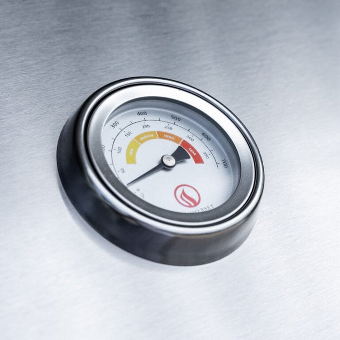 Close-up of stainless steel grill thermometer displaying temperature range from low to sear.