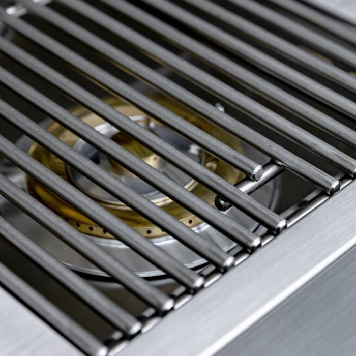 Close-up of stainless steel cooking grates showing brass burner beneath for even heat distribution on outdoor grill.