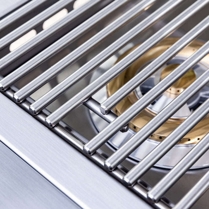 Close-up of stainless steel cooking grates with brass gas burner beneath, designed for even heat distribution and durability.