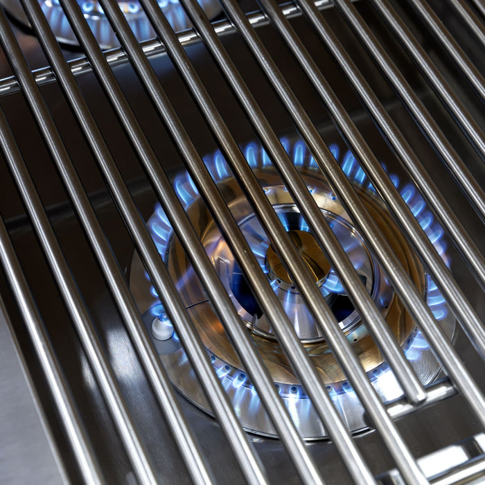 Close-up of stainless steel grill burner with blue flames beneath metal cooking grates for even outdoor heat distribution.