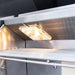 Close-up of stainless steel grill interior with bright halogen light illuminating the cooking area.