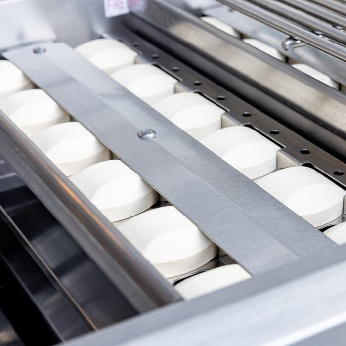 Close-up of stainless steel grill interior showing ceramic briquette heat distribution system.