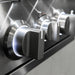 Close-up of stainless steel grill control knobs illuminated with white LED lighting.