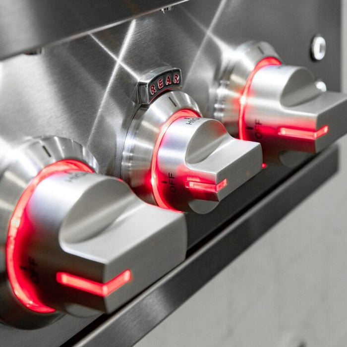 Close-up of stainless steel grill control knobs illuminated with red LED lighting.