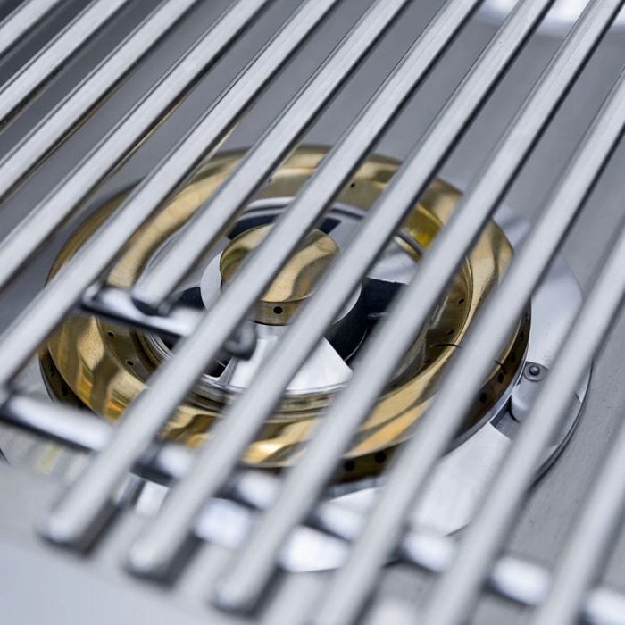 Close-up of a stainless steel side burner with brass burner visible beneath durable grill grates, showcasing a sleek and functional design.
