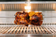 Rotisserie chicken cooking inside a stainless steel grill with interior lighting, showcasing even heat distribution and functionality.