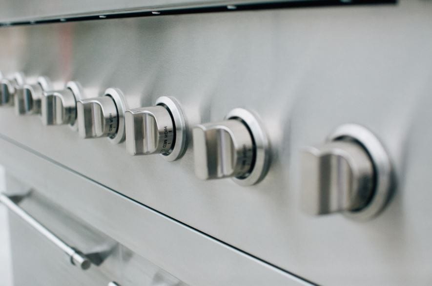 Close-up of stainless steel grill control knobs arranged in a row, showcasing precision design and durability for outdoor cooking.