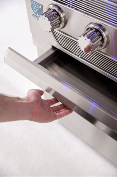 Close-up of a person opening the storage drawer on a stainless steel grill, showcasing control knobs and sleek modern design.