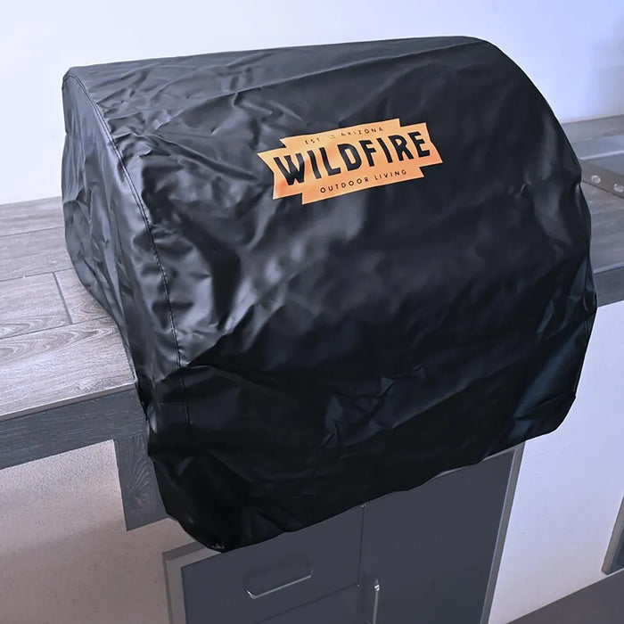 Alt text: Black outdoor grill cover draped over a stainless steel grill hood, protecting it from weather and elements.