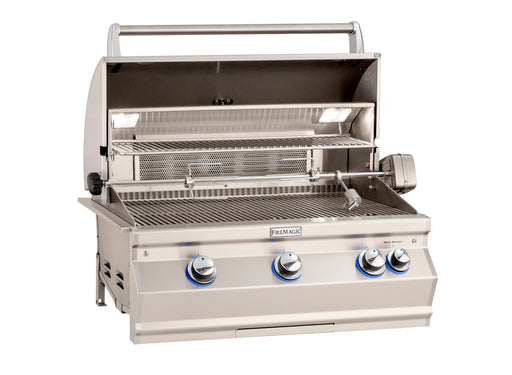 Open stainless steel gas grill with rotisserie kit, warming rack, interior lights, and blue LED-lit control knobs for outdoor cooking.