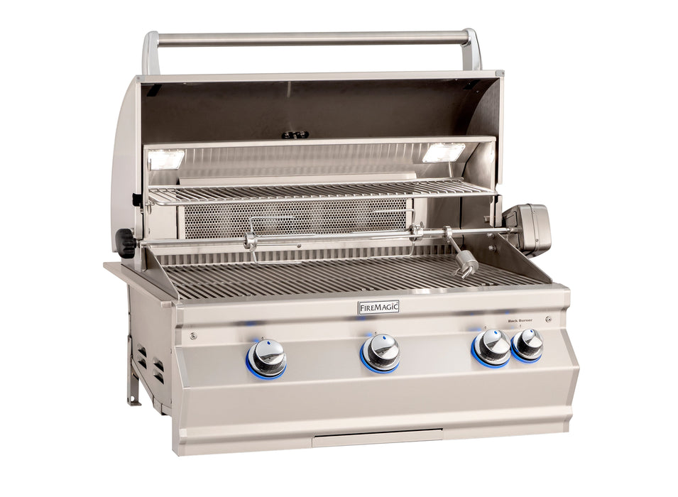 Open stainless steel gas grill with rotisserie kit, warming rack, interior lights, and blue LED-lit control knobs for outdoor cooking.