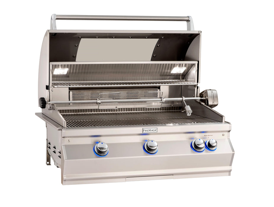 Open stainless steel gas grill with rotisserie kit, interior lights, warming rack, and four blue LED-lit control knobs for outdoor cooking.