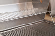 Interior view of stainless steel grill showing main cooking grate and elevated warming rack for versatile grilling options.