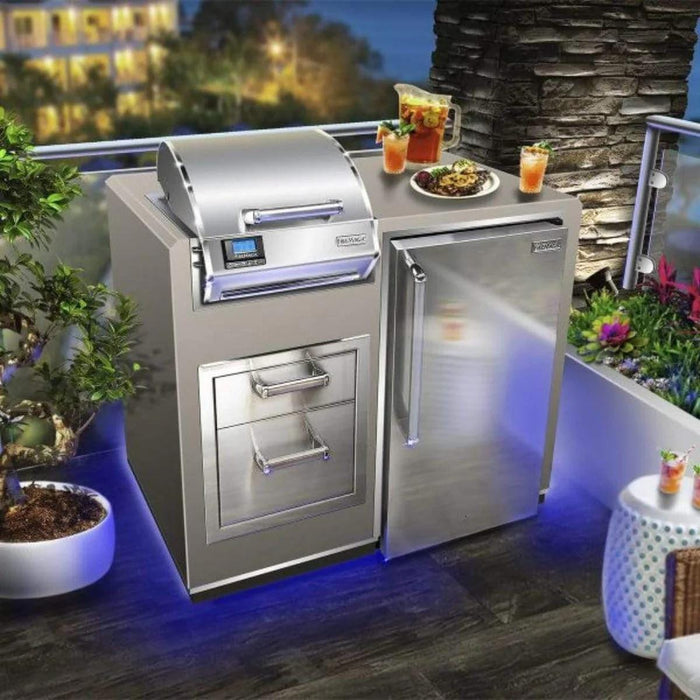 Modern outdoor kitchen setup with stainless steel grill, refrigerator, drawers, drinks, and food on counter, with blue LED lighting.