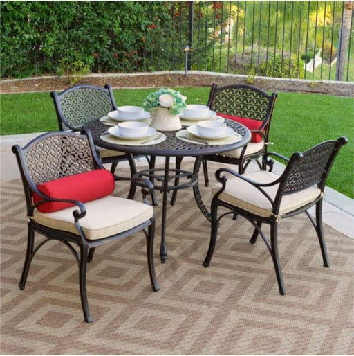 Elegant 5-piece outdoor patio dining set with a round metal table, four cushioned chairs, and decorative accents on a patio with greenery.