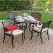 Elegant 5-piece outdoor patio dining set with a round metal table, four cushioned chairs, and decorative accents on a patio with greenery.