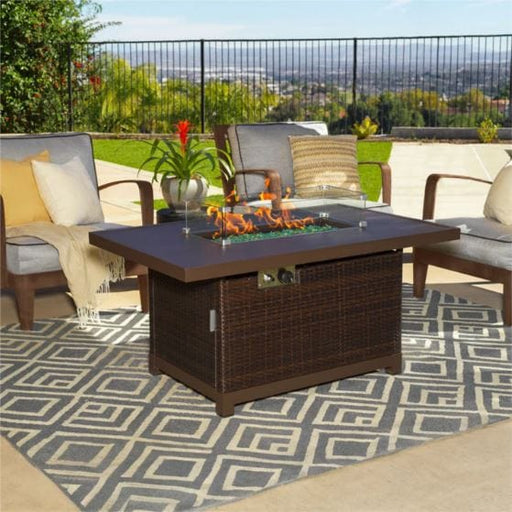 Outdoor patio setup featuring a rectangular fire pit table with a wicker base, surrounded by cozy seating and a geometric-patterned rug.