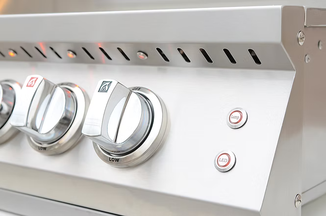 Close-up of a stainless steel gas grill control panel showing metal burner knobs and built-in ignition and LED light buttons.
