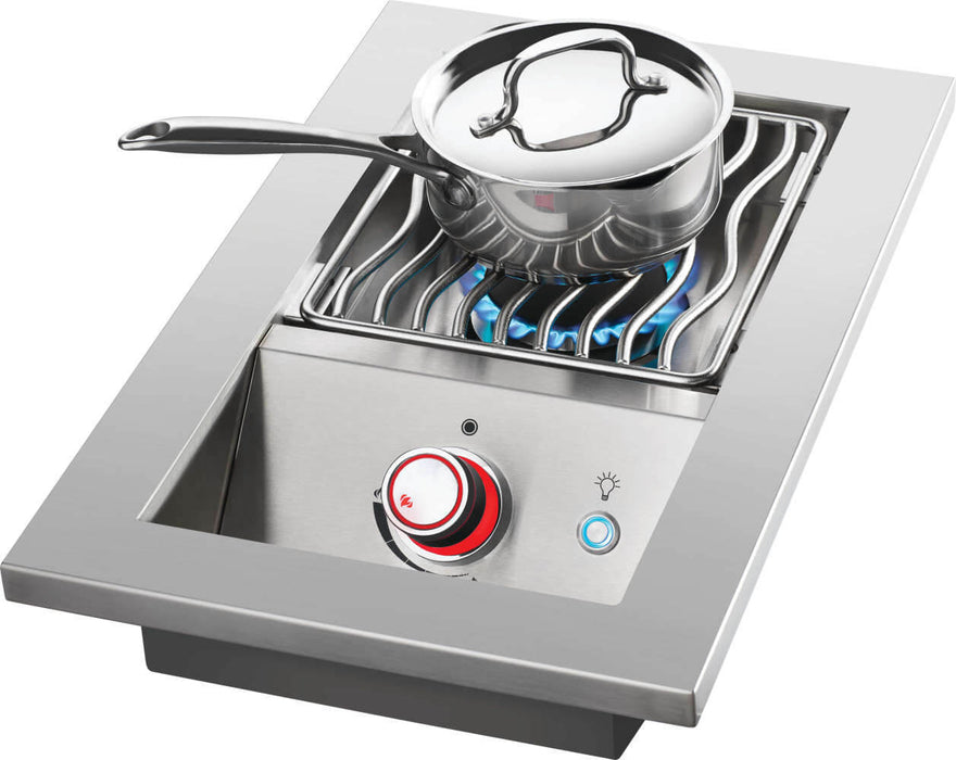 Stainless steel outdoor burner with a saucepan on wavy grill grates, blue flame visible, and a red-lit control knob for precise cooking.