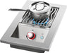 Stainless steel outdoor burner with a saucepan on wavy grill grates, blue flame visible, and a red-lit control knob for precise cooking.