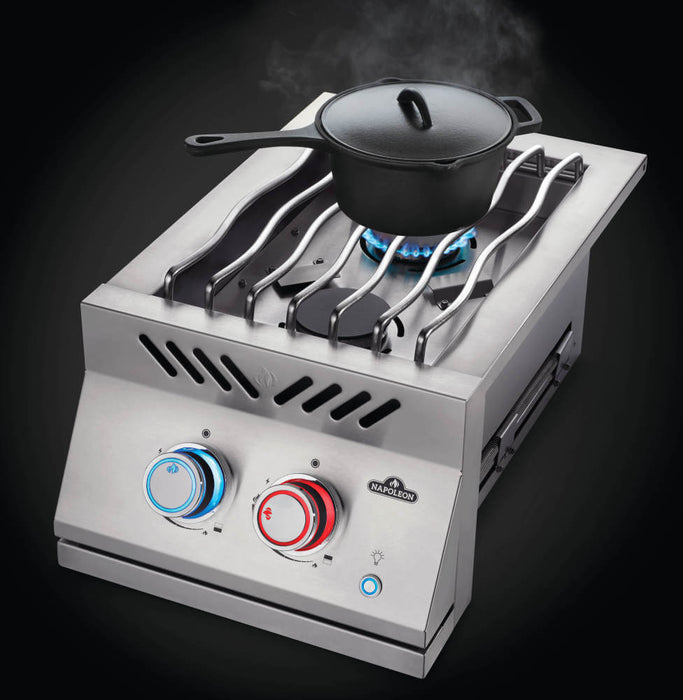 Stainless steel double burner with wavy grill grates, blue flame, red and blue-lit knobs, and a black pot placed on one burner.