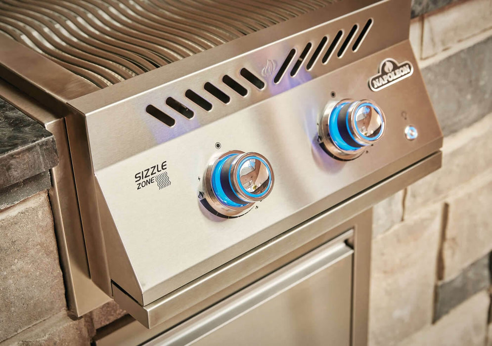 Built-in stainless steel double burner with blue-lit control knobs, wavy grill grates, and vented design, integrated into an outdoor kitchen.