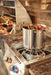 Outdoor kitchen with a stainless steel burner holding a large pot of food, blue and red-lit control knobs, and a built-in grill nearby.