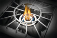 Close-up of a stainless steel outdoor burner with a circular grate and a blue and yellow flame, designed for high-heat cooking.