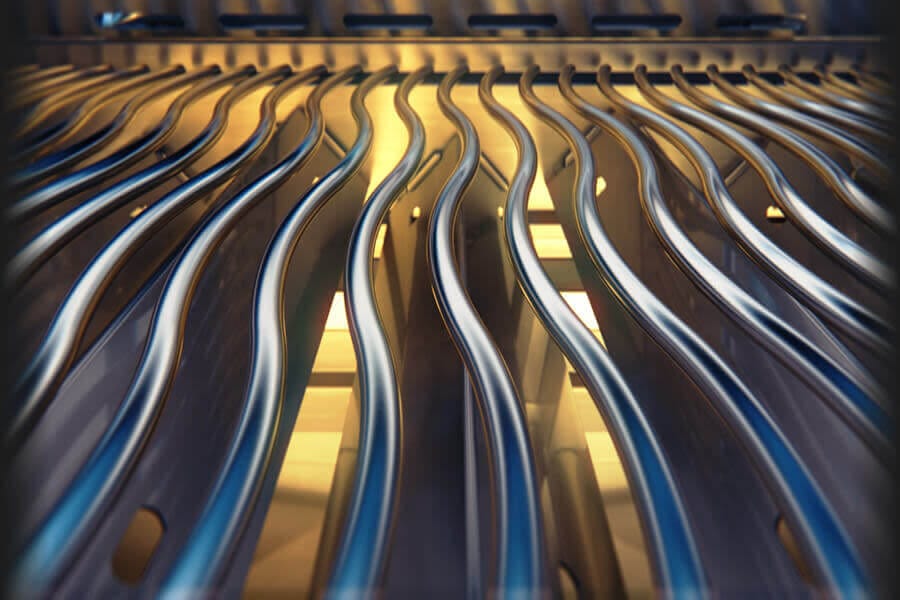 Close-up of stainless steel wavy grill grates with glowing heat underneath, designed for even cooking and searing.