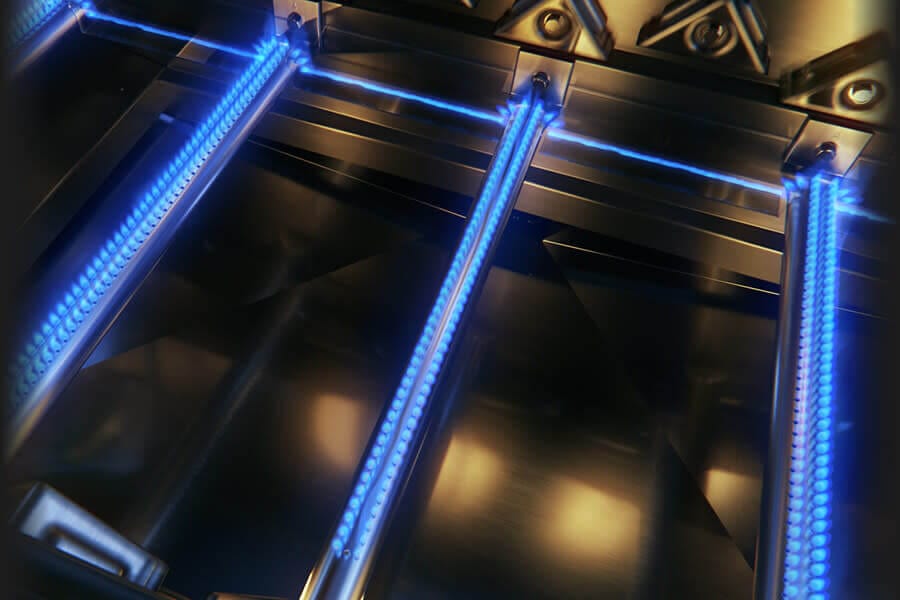 Close-up of blue flame burners inside a stainless steel gas grill, showcasing evenly distributed heat for efficient cooking.