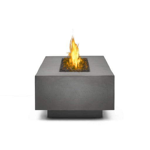 Close-up view of a modern rectangular fire table with a gray concrete finish, showcasing a central fire feature with glowing flames.