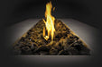 Close-up of a rectangular fire pit filled with lava rocks and a glowing flame in the center, set against a dark background.