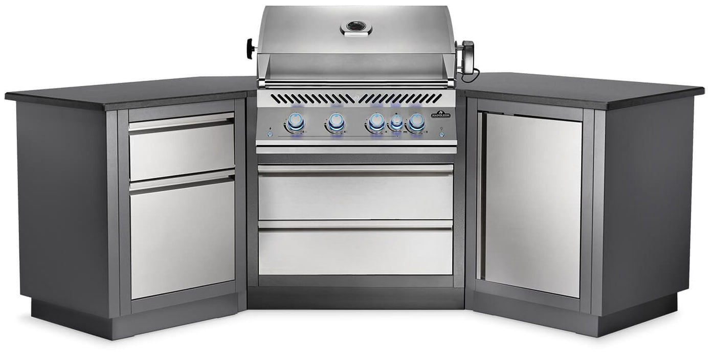 Outdoor kitchen setup featuring a built-in stainless steel gas grill with blue-lit knobs, flanked by corner storage drawers and cabinets.