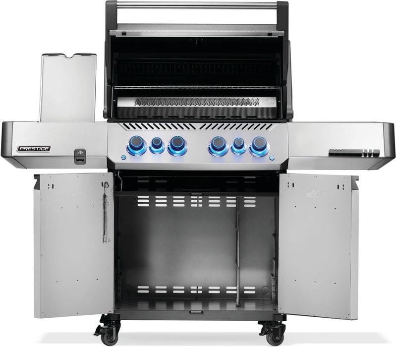 A stainless steel grill with open cabinet doors showing internal storage space, illuminated control knobs, and a raised cooking hood.