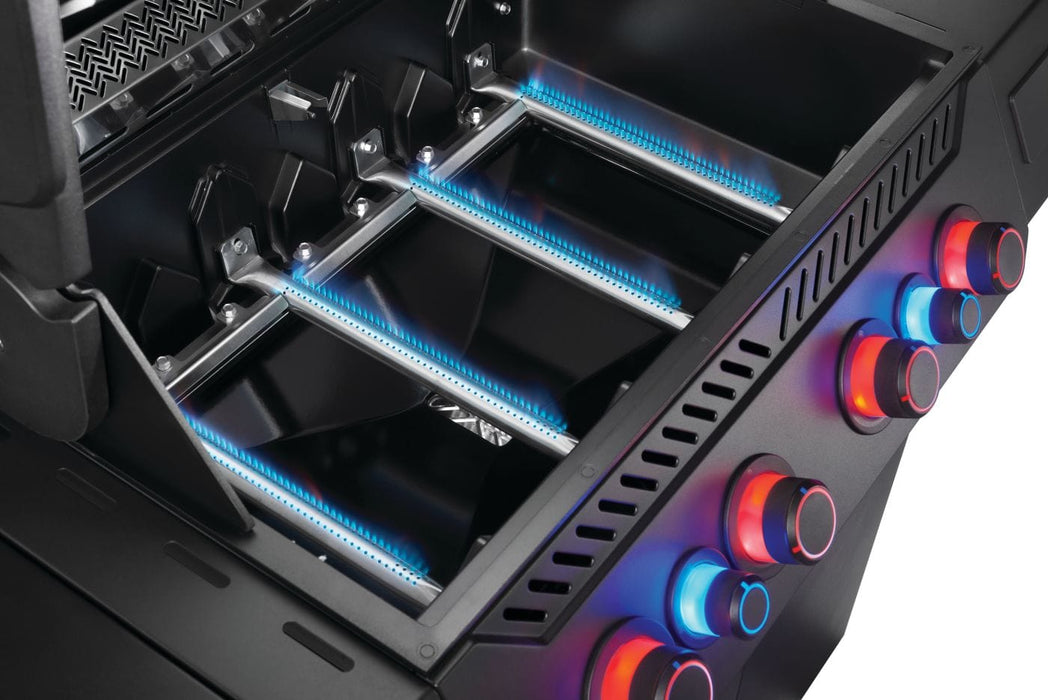 Close-up view of grill burners with blue flames, sleek black interior, and illuminated red and blue control knobs on the side.