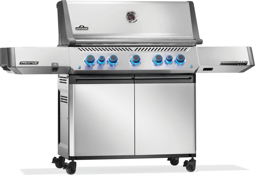 Freestanding stainless steel gas grill with illuminated control knobs, double doors for storage, and side shelves on caster wheels.