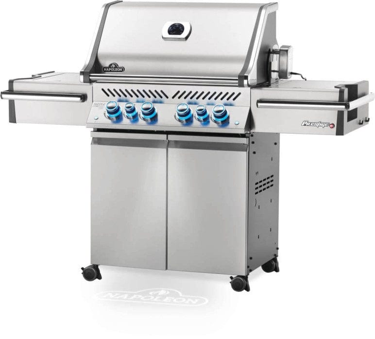 Angled view of stainless steel freestanding gas grill with six control knobs, side shelves, and enclosed cabinet, featuring a sleek design and mobility wheels