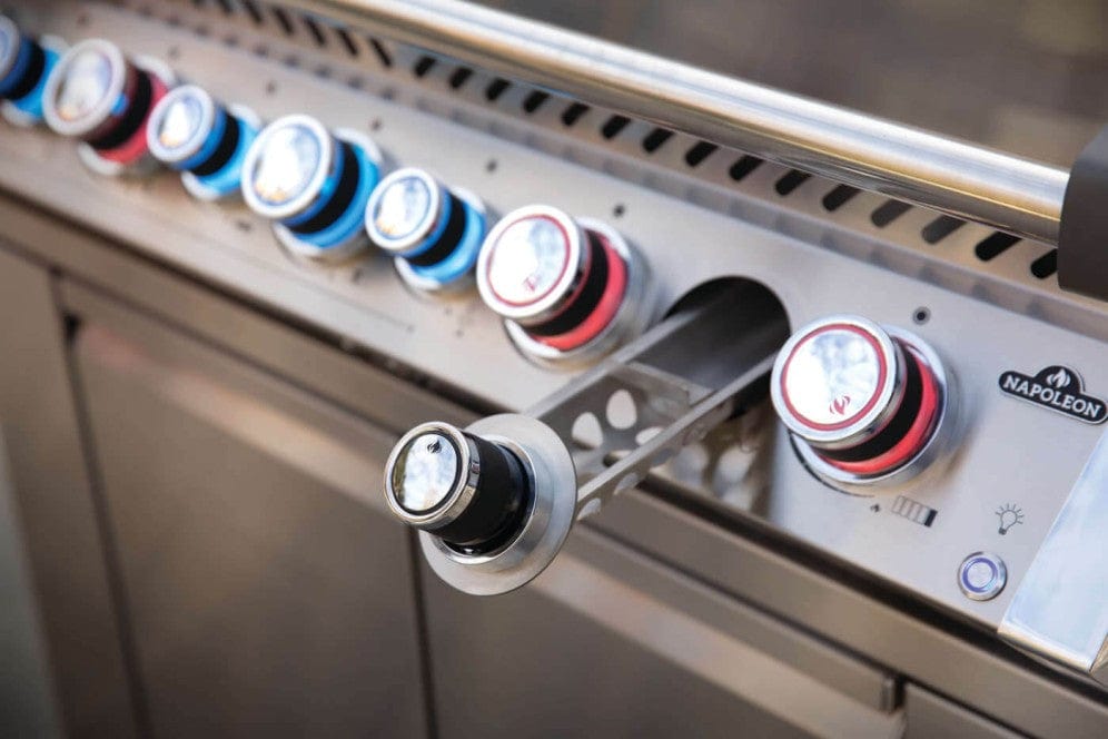 Close-up of illuminated grill control knobs with sleek stainless steel finish and integrated rotisserie handle for precision cooking