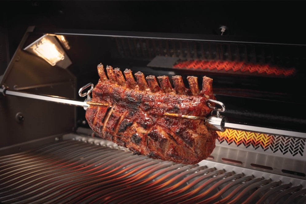 Close-up of a rotisserie inside a grill, cooking a perfectly roasted rack of ribs with interior lighting and infrared burner glowing