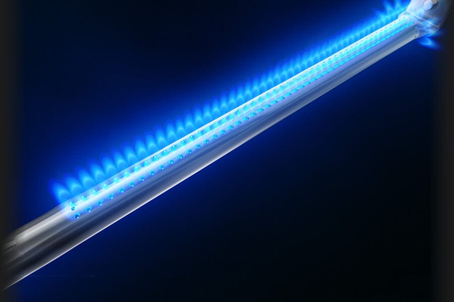 Close-up view of a stainless steel burner with bright blue flames evenly distributed along its surface in a dark background.