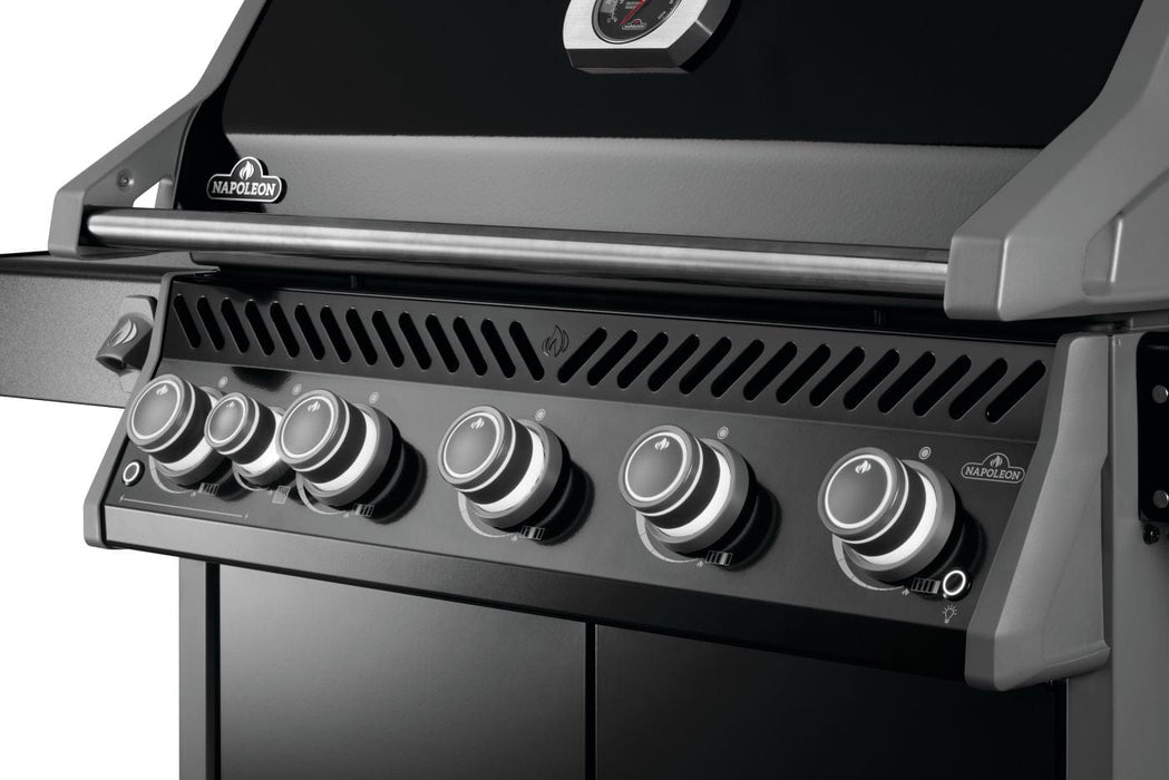 Close-up of a grill's front panel showing control knobs, vented panel, and part of the black lid with a built-in thermometer.