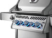 Close-up of a gas grill showing illuminated control knobs, a temperature gauge on the lid, and a side burner control.