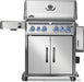 Front view of a stainless steel barbecue grill with illuminated control knobs, dual-door storage cabinet, and side burner attachment.