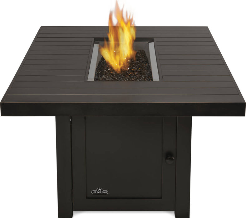 Fire table with a bronze slatted top, featuring a central fire pit with flames and black lava rocks, supported by a base cabinet.