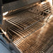 Stainless steel grill interior showing main cooking grates and adjustable warming rack under built-in lights.