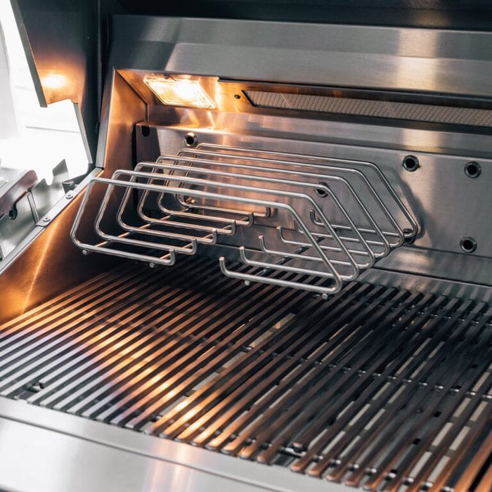 Stainless steel grill interior featuring main cooking grates, warming rack, and built-in lighting for visibility.