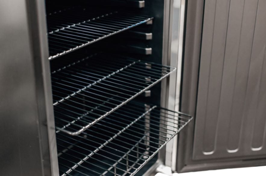 Close-up view of an open refrigerator showing adjustable wire shelves and a partially opened shelf, highlighting interior storage.