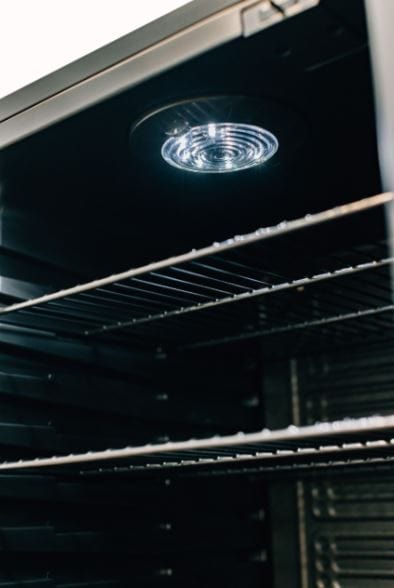 Interior view of a refrigerator featuring wire shelves and a bright LED light at the top, highlighting the sleek and spacious design.