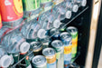 Close-up of a refrigerator shelf stocked with bottled water, canned beverages, and drinks arranged neatly for easy access.