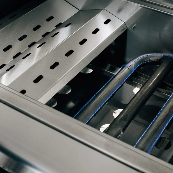 Close-up of a stainless steel grill showing perforated heat plates and two active burners with visible blue flames underneath.